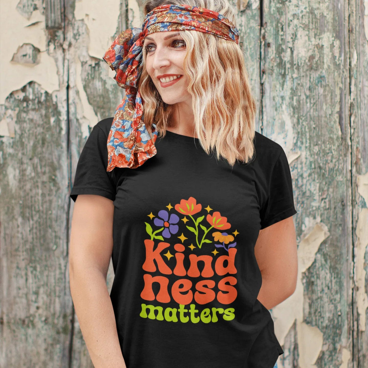 Woman wearing a black t-shirt with 'Kindness Matters' design against a wooden background