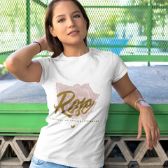 Woman wearing a white t-shirt with 'Rejoice' design, standing against a green metal fence.