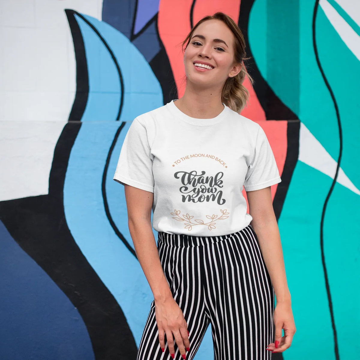 Woman wearing a white t-shirt with text in front of a colorful abstract mural