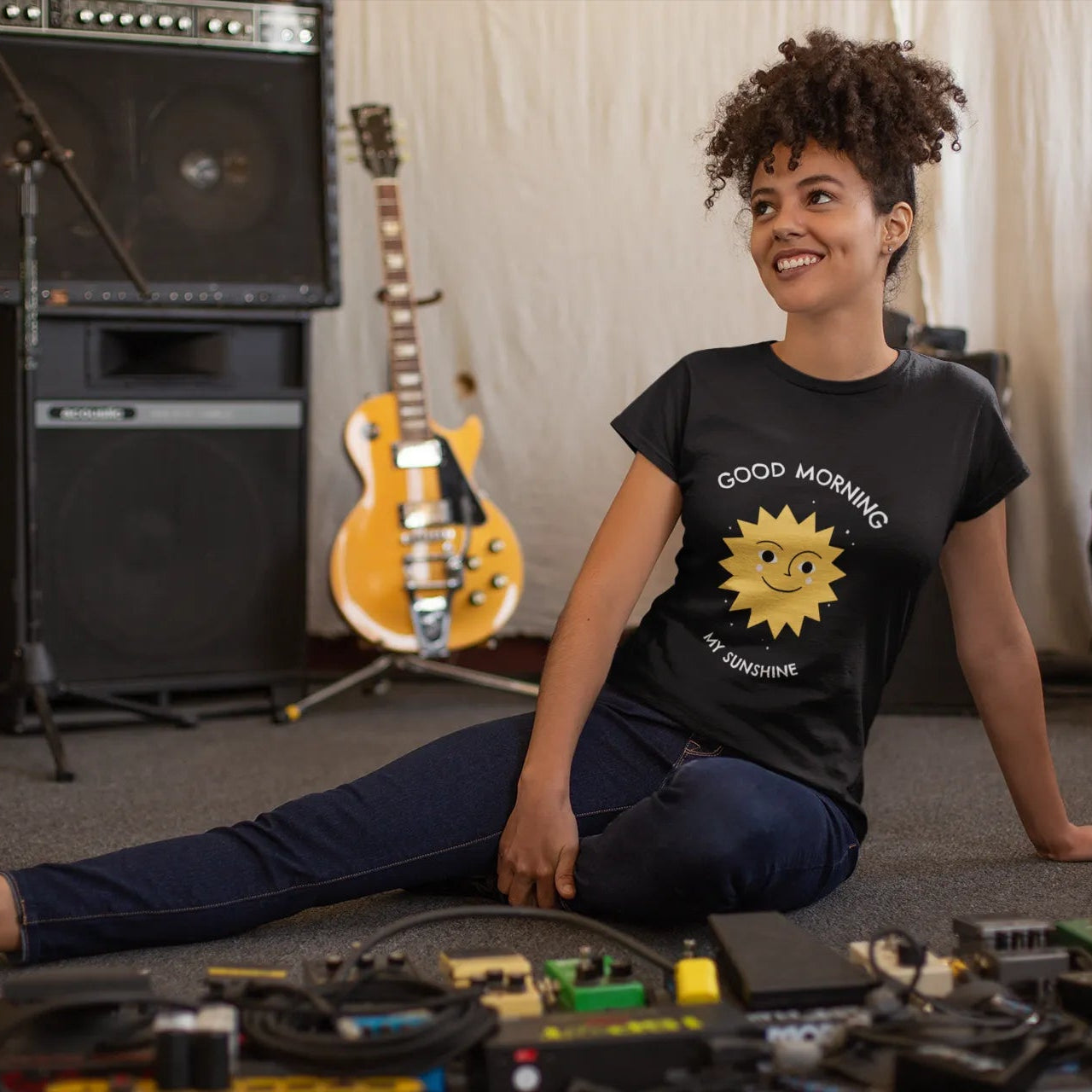 Person sitting on the floor with toys, surrounded by musical instruments in a room.