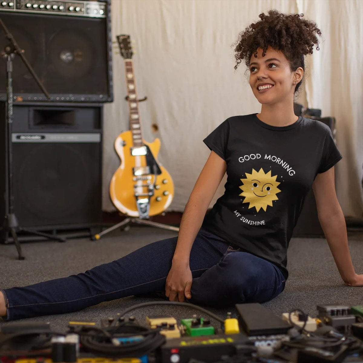 Person sitting on the floor with toys, surrounded by musical instruments in a room.