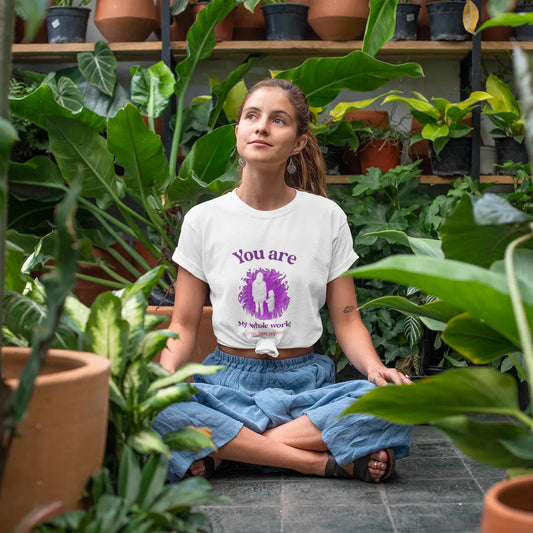 Woman sitting among plants wearing a t-shirt with a motivational quote.