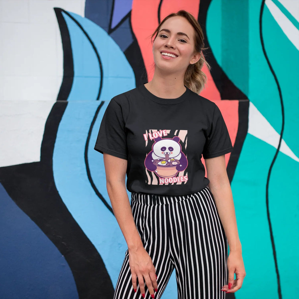 Woman wearing a black t-shirt with a graphic design in front of a colorful abstract wall.