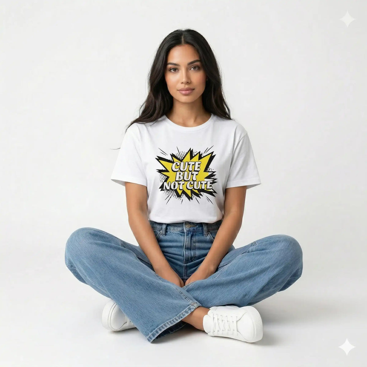 Person wearing a white t-shirt with a graphic design and text, sitting on the floor against a white background.