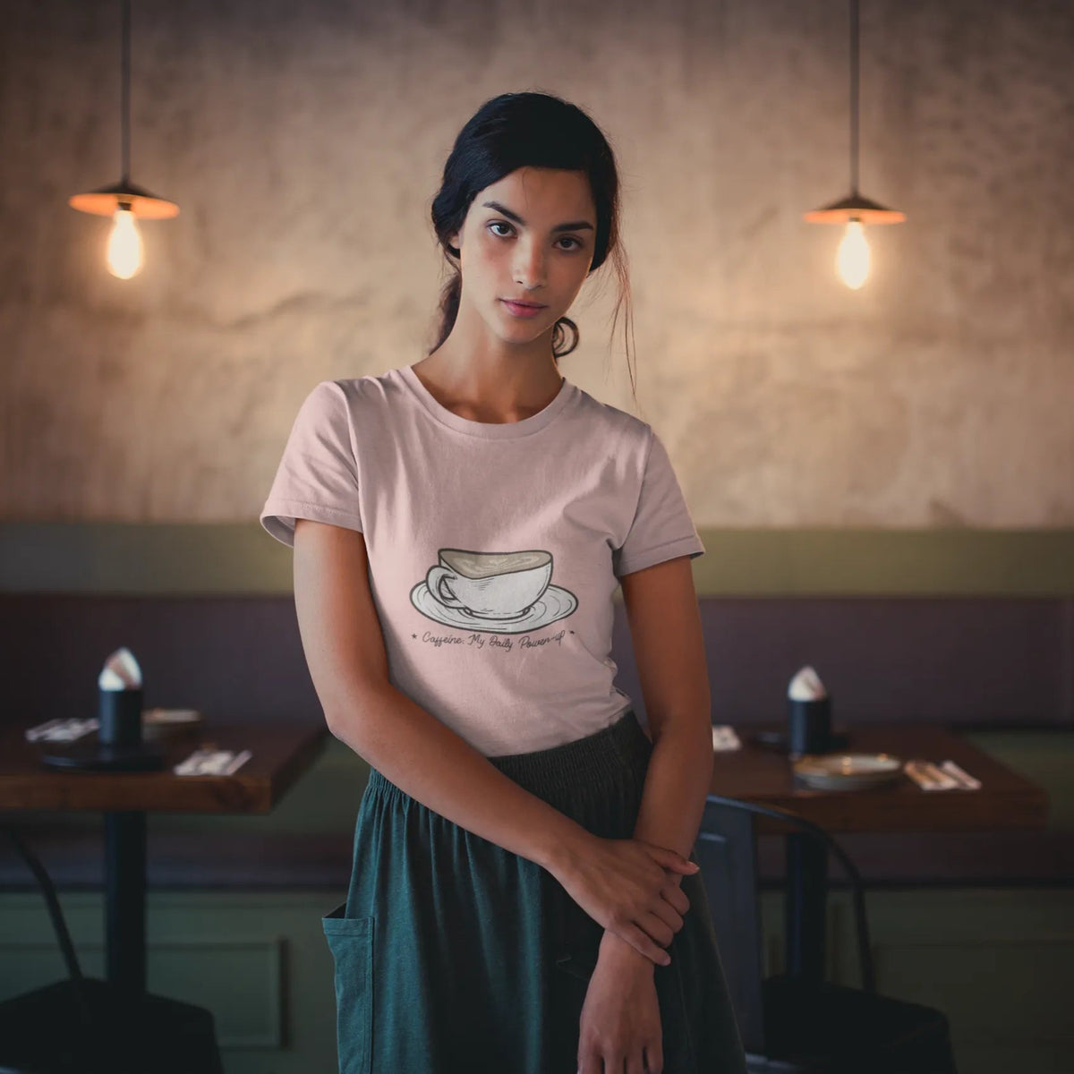 Woman wearing a pink t-shirt with a coffee cup design in a café setting