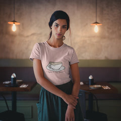 Woman wearing a pink t-shirt with a coffee cup design in a café setting