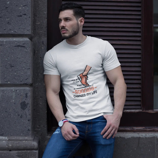 Man wearing a white t-shirt with a graphic design leaning against a stone wall.