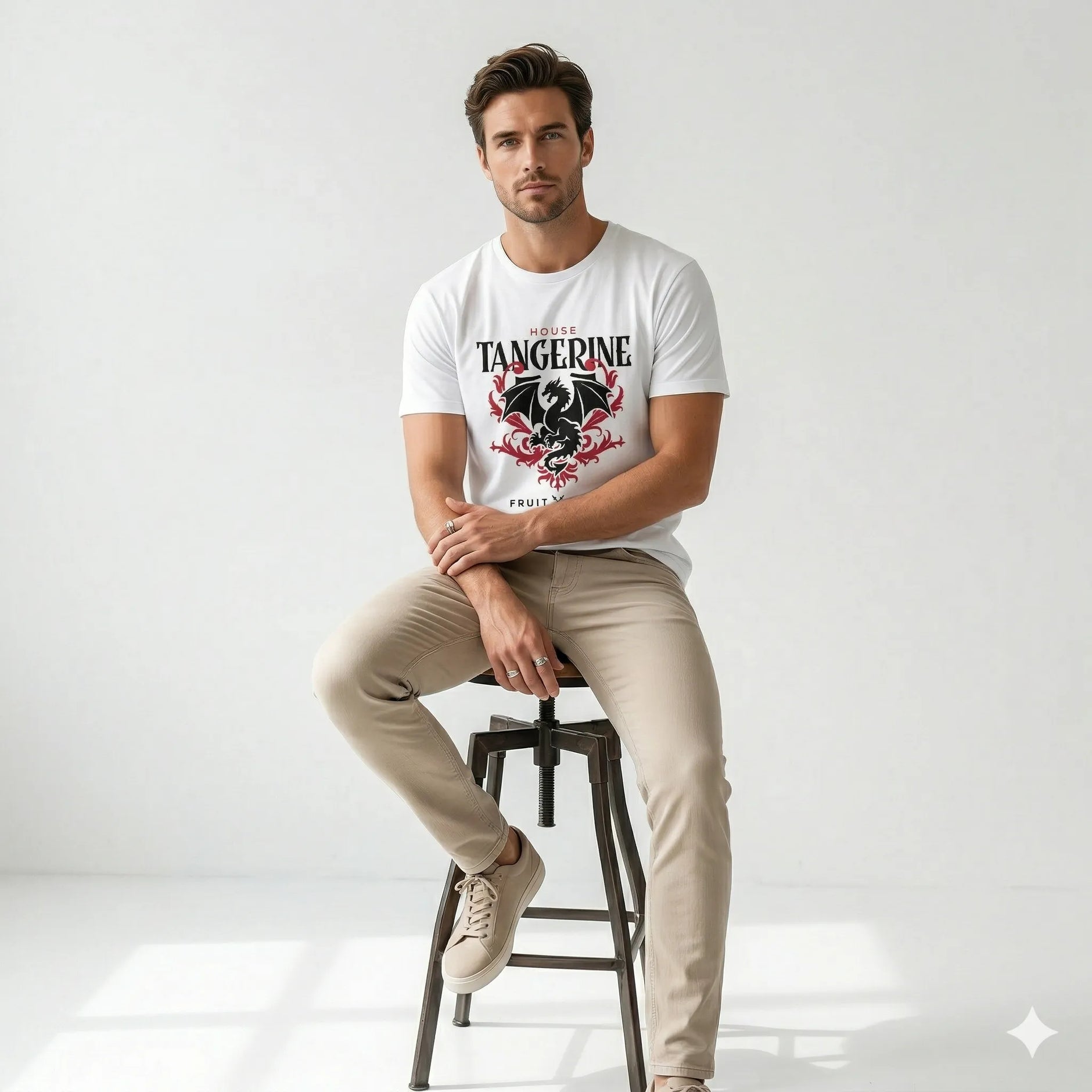 Man sitting on a stool wearing a white t-shirt with a graphic design and text.