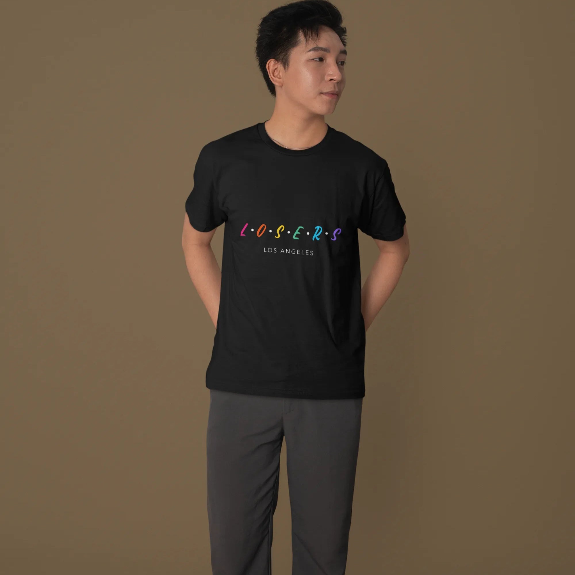 Person wearing a black t-shirt with colorful text on a brown background