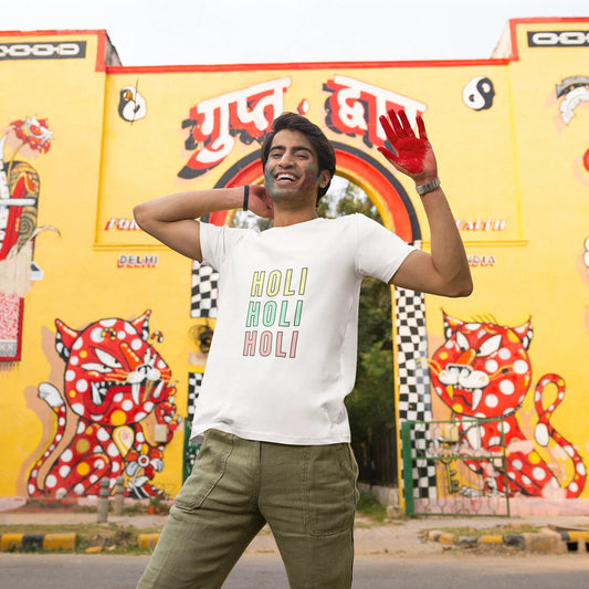 Person wearing a 'Holi Holi Holi' shirt in front of a colorful mural.