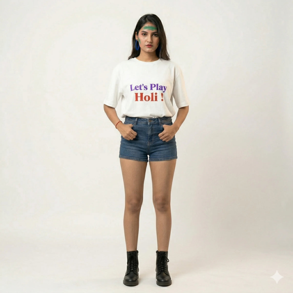 Person wearing a white t-shirt with 'Let's Play Holi!' text and denim shorts on a white background