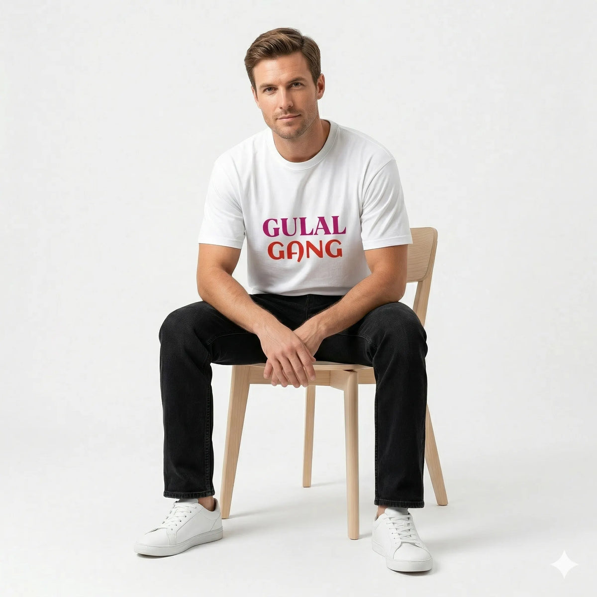 Man sitting on a chair wearing a white t-shirt with 'GULAL GANG' text.