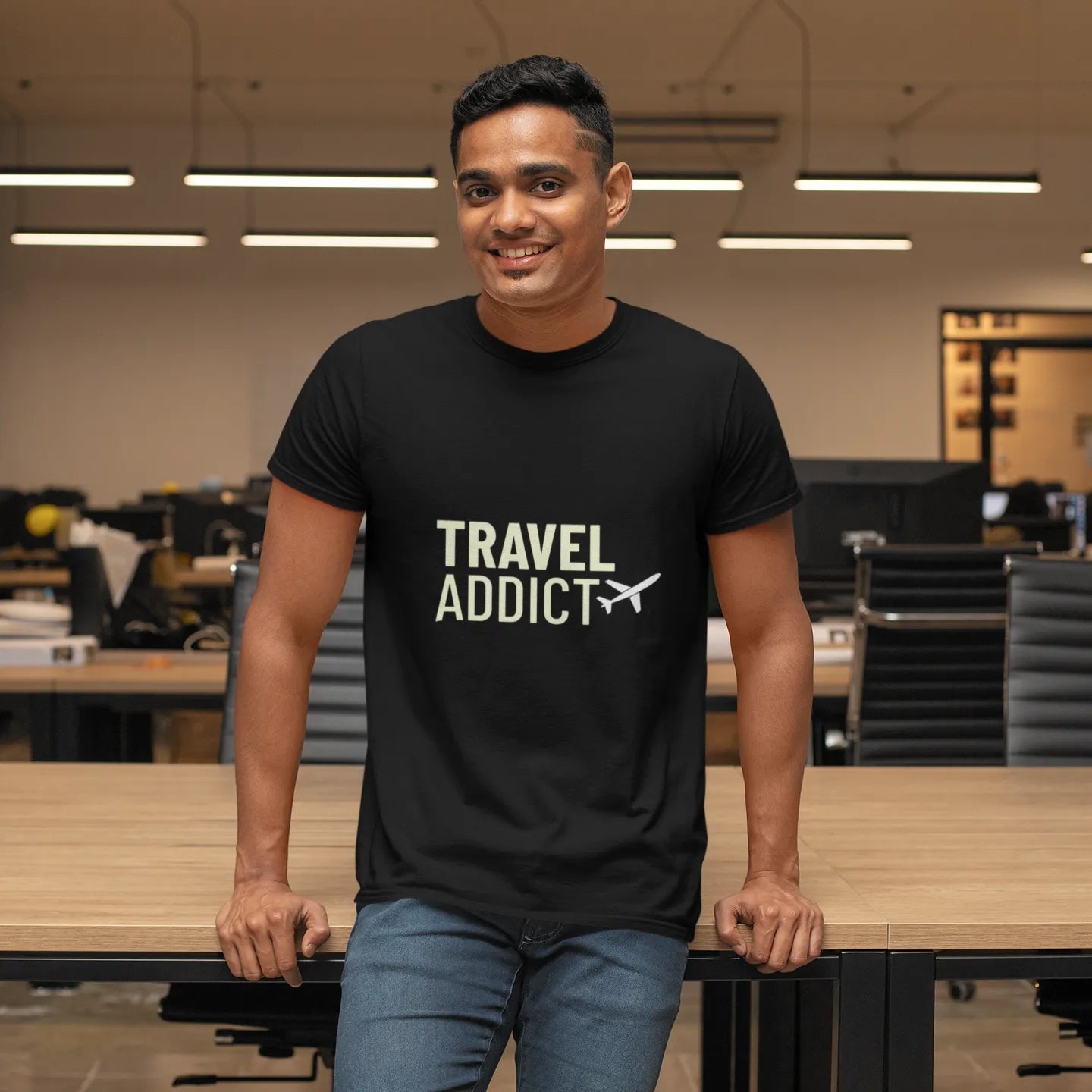 Man wearing a black t-shirt with 'Travel Addict' text in an office setting