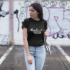 Woman wearing a black t-shirt with 'Airplane Mode' text in front of a graffiti-covered wall.