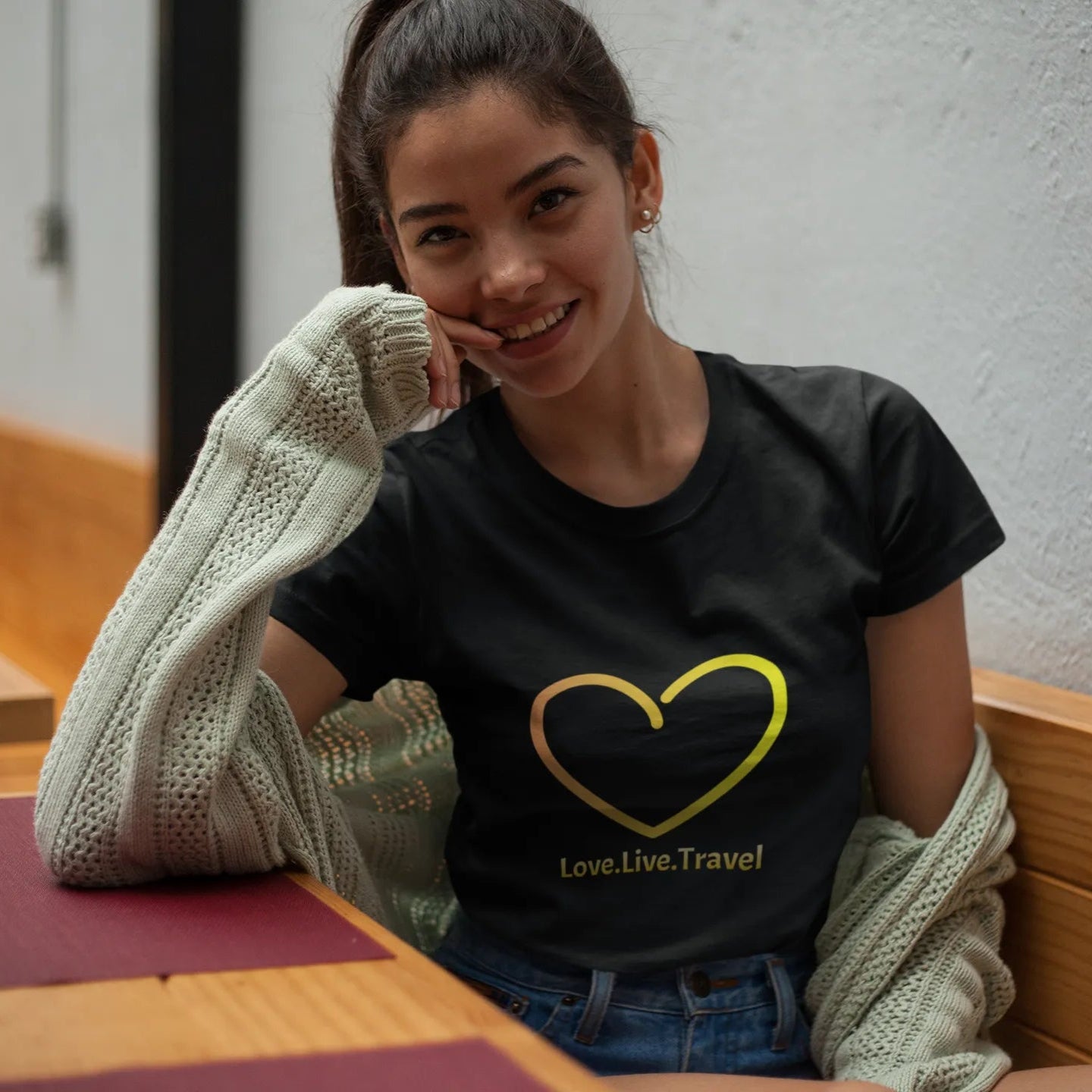Woman wearing a black t-shirt with a yellow heart design, sitting at a table.