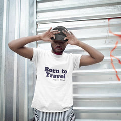 Person wearing a 'Born to Travel' t-shirt against a metal wall with graffiti.