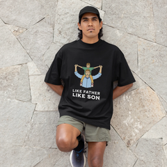 Man wearing a black t-shirt with graphic design and text, standing against a stone wall.