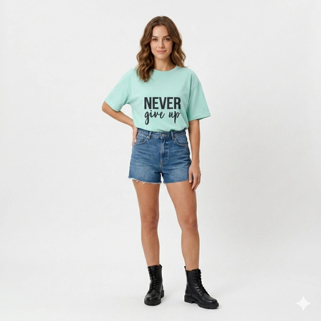 Woman wearing a light blue t-shirt with 'Never Give Up' text, denim shorts, and black boots on a white background
