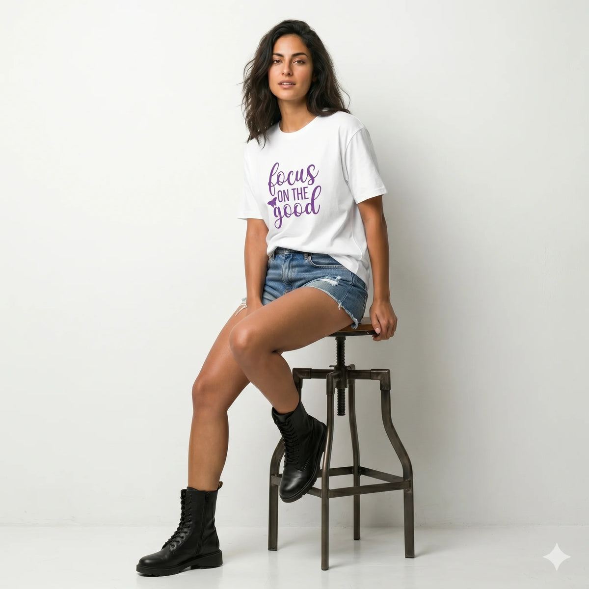 Person wearing a white t-shirt with 'focus on the good' text in purple outdoors.
