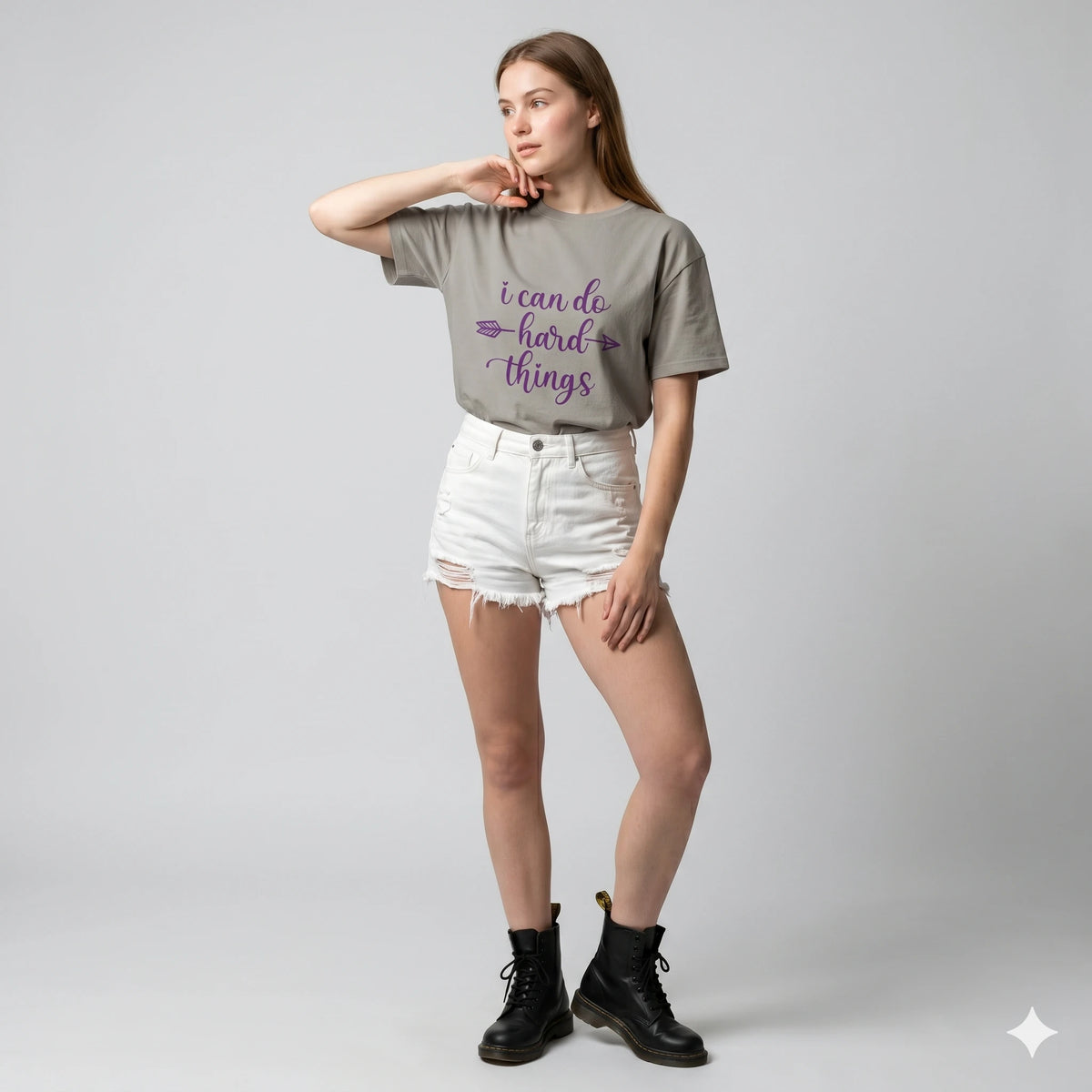 Woman wearing a gray t-shirt with a motivational quote on a plain background