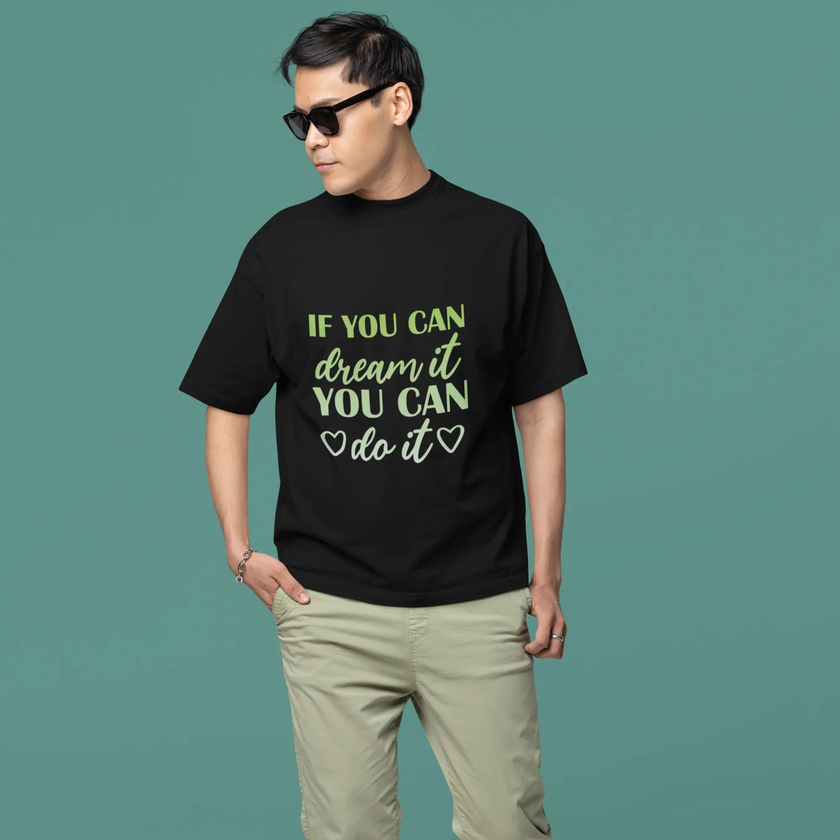 Man wearing a black t-shirt with motivational quote on a teal background