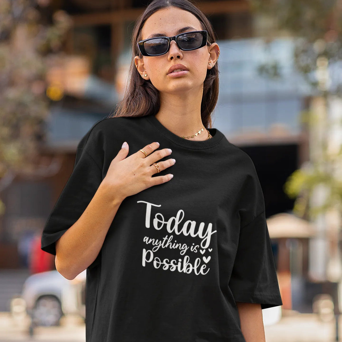 Woman wearing a black t-shirt with 'Today anything is possible' text on a street.
