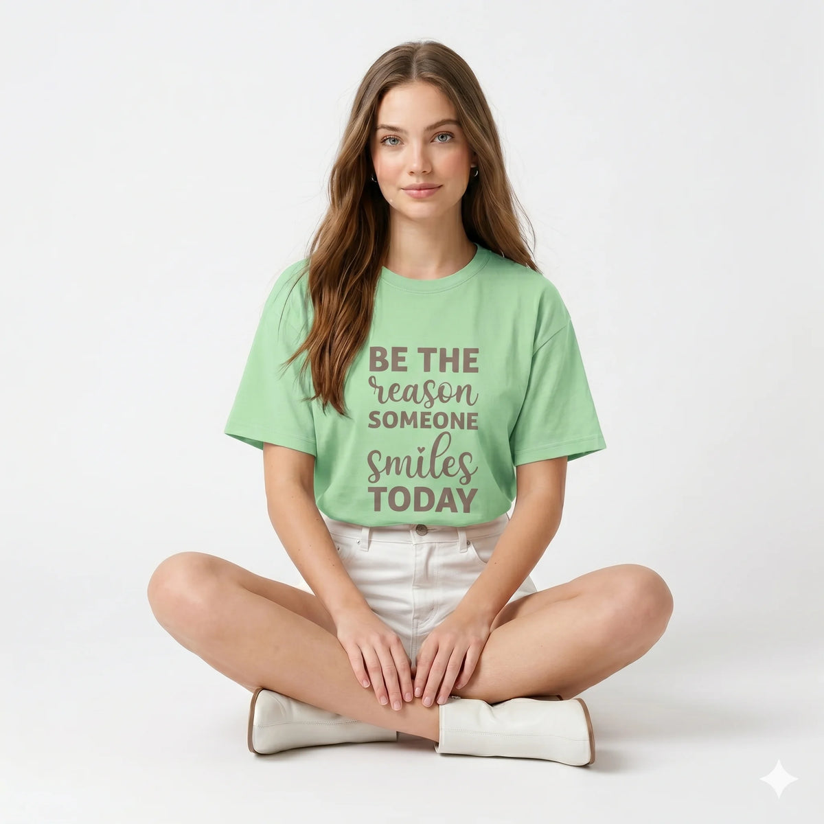 Woman wearing a light green t-shirt with a motivational quote against a geometric-patterned wall.