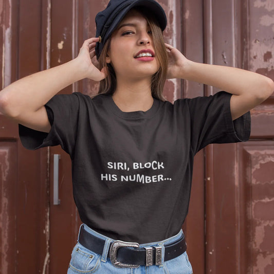 Person wearing a black t-shirt with text and blue shorts against a brown wall.