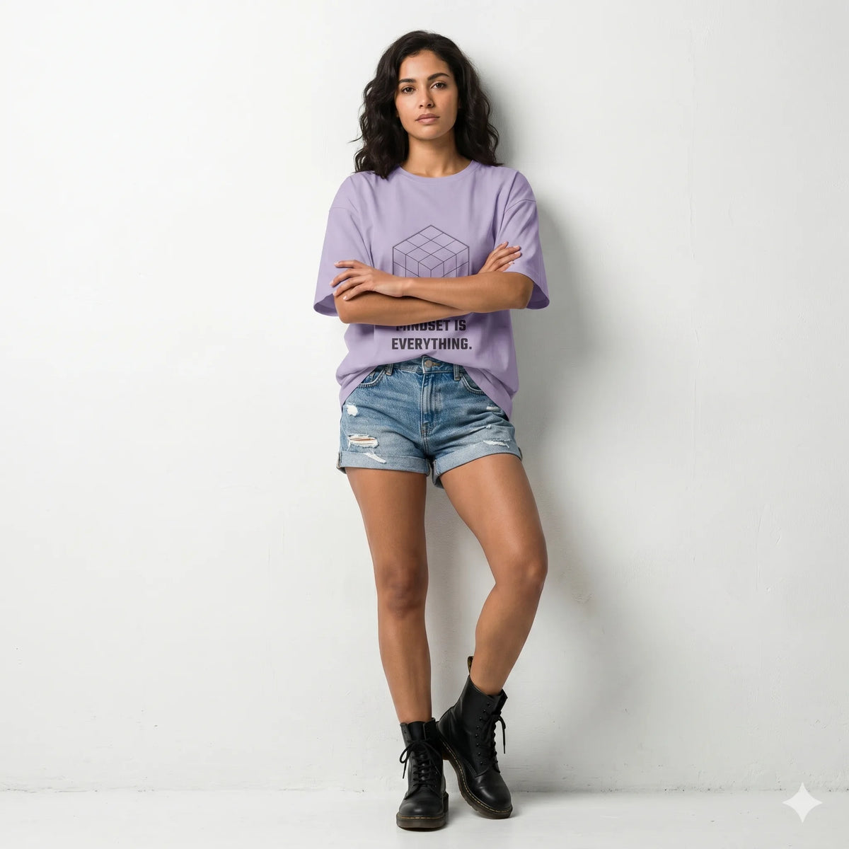 Woman wearing a light purple t-shirt with text, beige skirt, and white sneakers on a light purple background