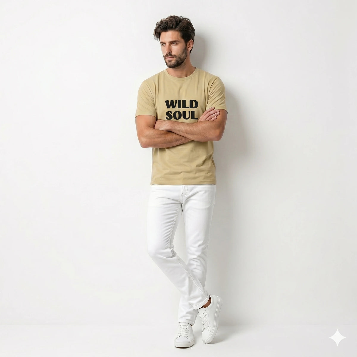 Man wearing a beige t-shirt with 'WILD SOUL' text and white pants on a light background