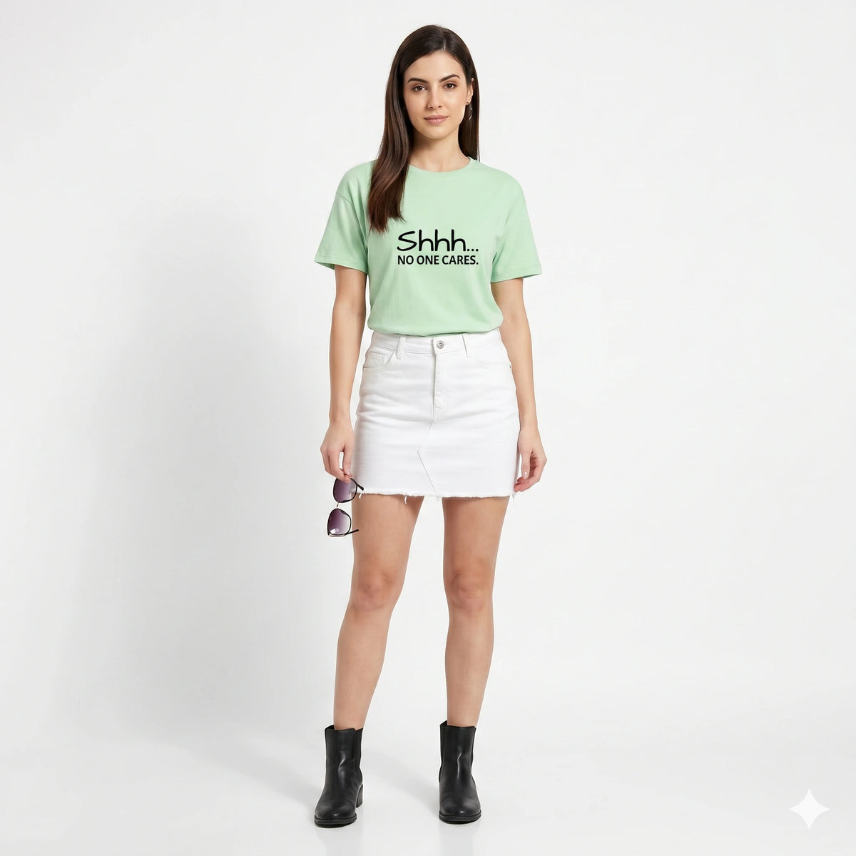 Woman wearing a light green t-shirt with text and a white skirt on a white background