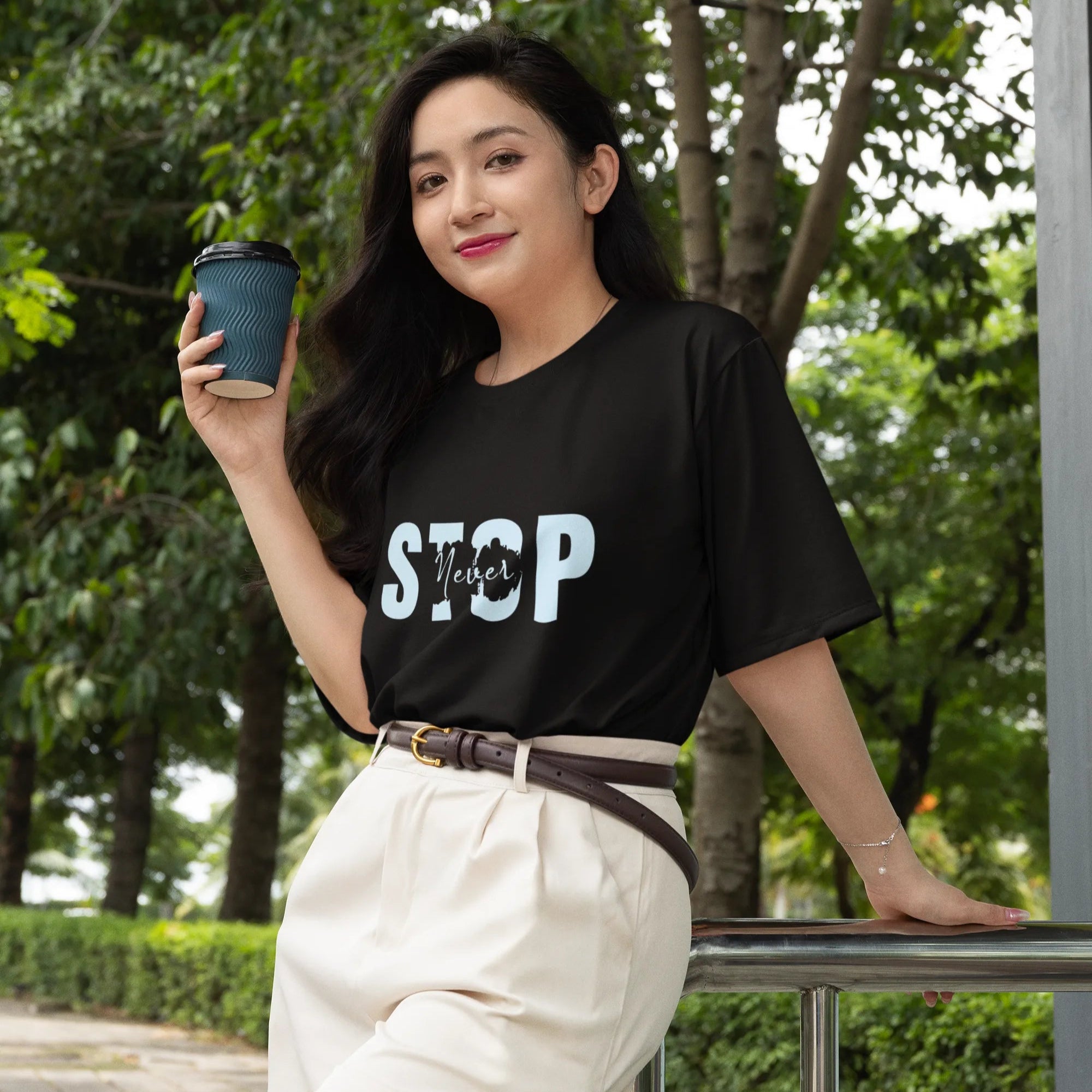Woman holding a coffee cup outdoors with greenery in the background