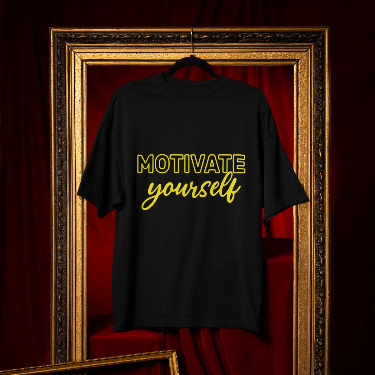 Black t-shirt with 'Motivate yourself' text on a hanger against a red curtain background.