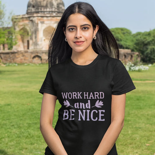 Person wearing a black t-shirt with 'Work Hard and Be Nice' text in an outdoor setting.