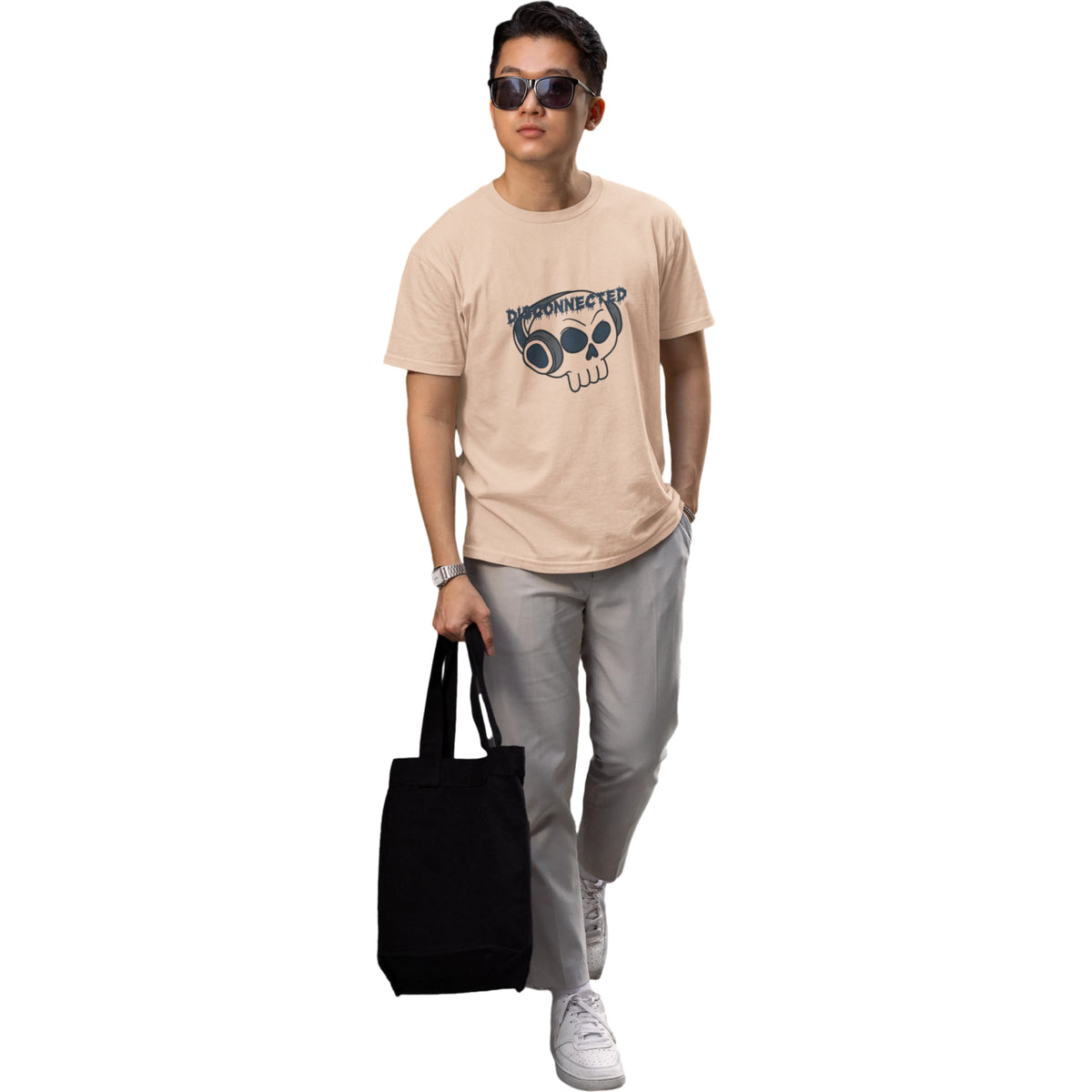 Person wearing a beige t-shirt with a graphic design, holding a black tote bag on a white background