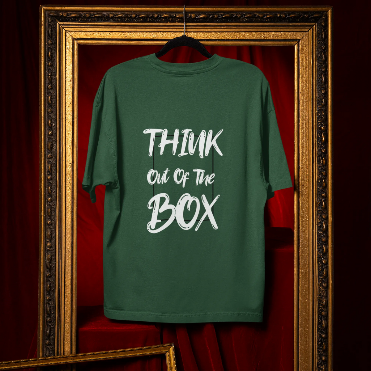 Green t-shirt with 'Think Out of the Box' text hanging in a decorative frame.