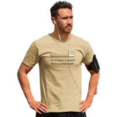 Man wearing a beige t-shirt with text and earphones, standing against a white background