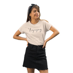 Woman wearing a beige t-shirt with 'Enjoying' text and a black skirt on a white background