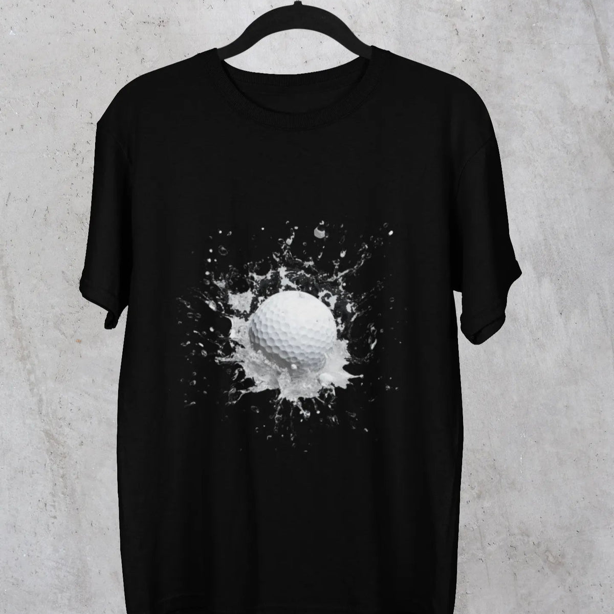 Black t-shirt with a graphic design of a golf ball on a hanger against a textured gray background