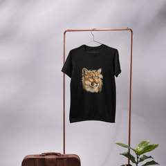 Black t-shirt with a lion graphic on a copper rack, next to a brown suitcase and potted plant.