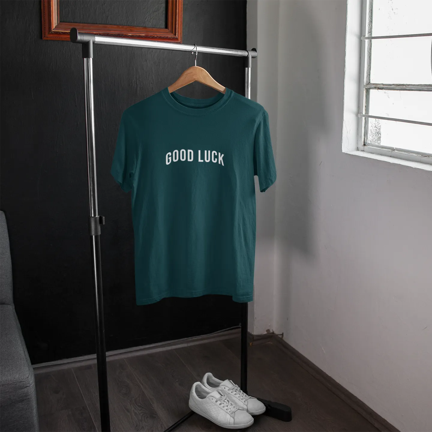 Green t-shirt with 'GOOD LUCK' text on a hanger in a room with a window.
