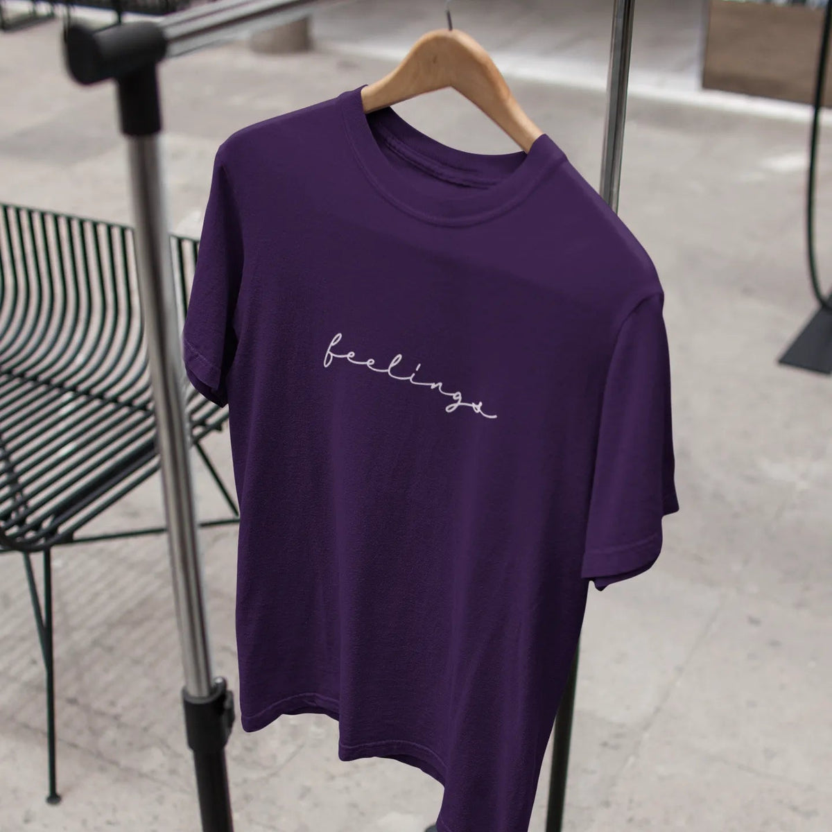 Purple t-shirt with 'feelings' text on a hanger against a neutral background