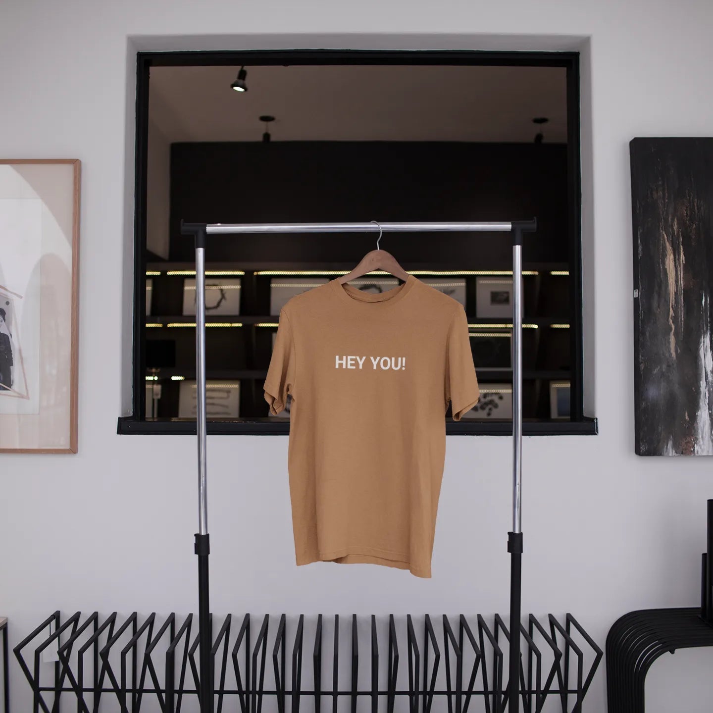 Beige t-shirt with 'HEY YOU!' text hanging in a modern interior setting.