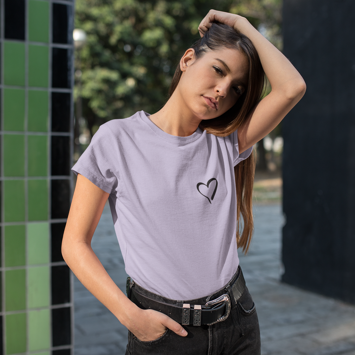 Woman wearing a light purple t-shirt with a black heart design outdoors.