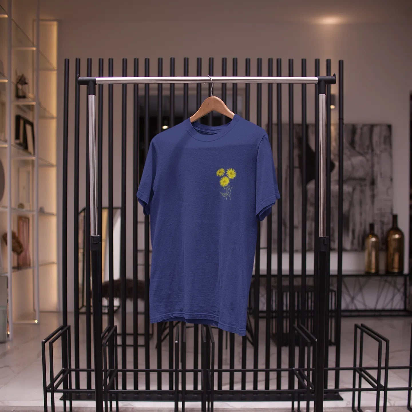 Blue t-shirt with a yellow graphic on a black metal rack.