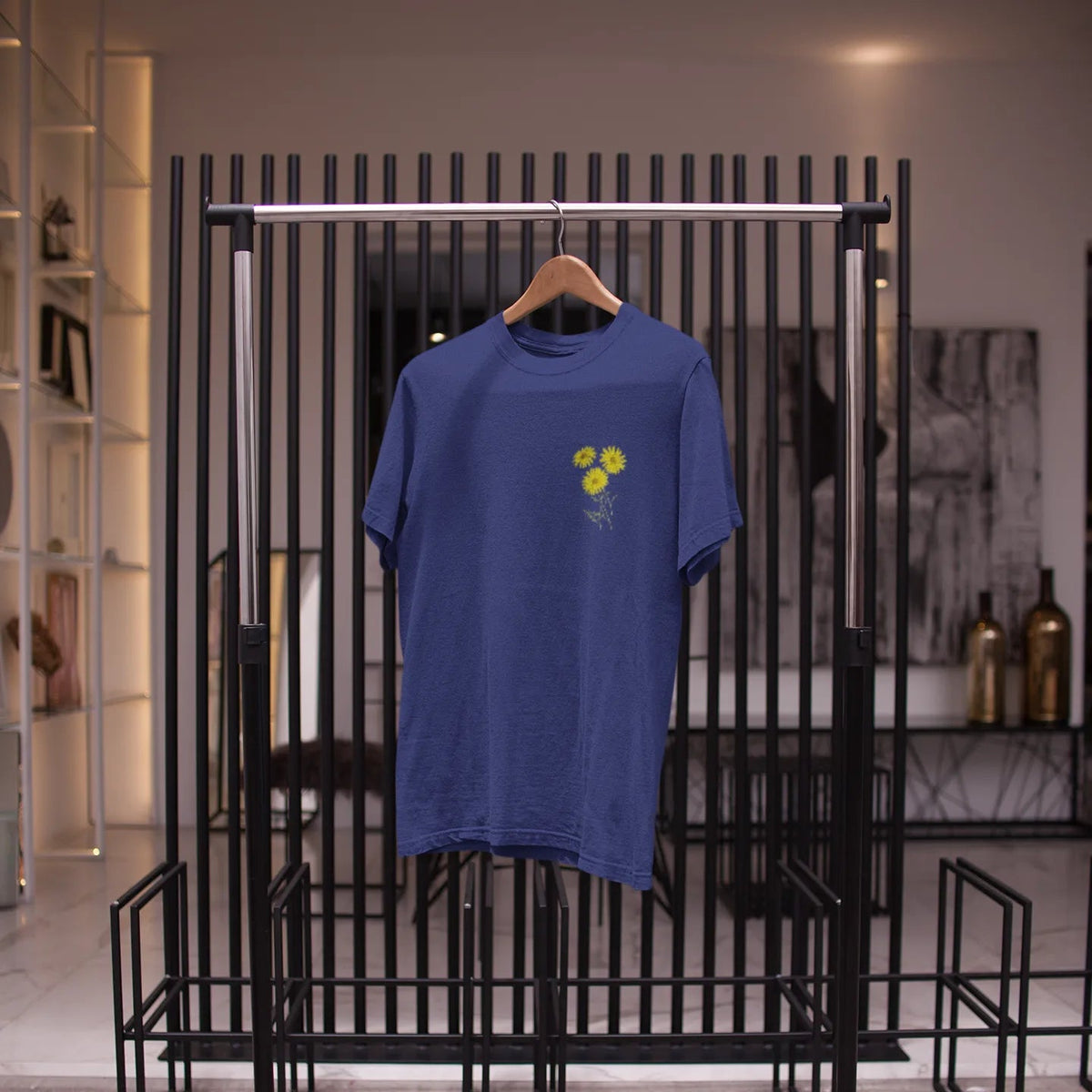 Blue t-shirt with a yellow graphic on a black metal rack.