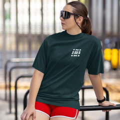 Woman wearing a dark green t-shirt with text and red shorts outdoors.