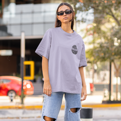 Person wearing a oversized light purple t-shirt and ripped jeans on a city street.