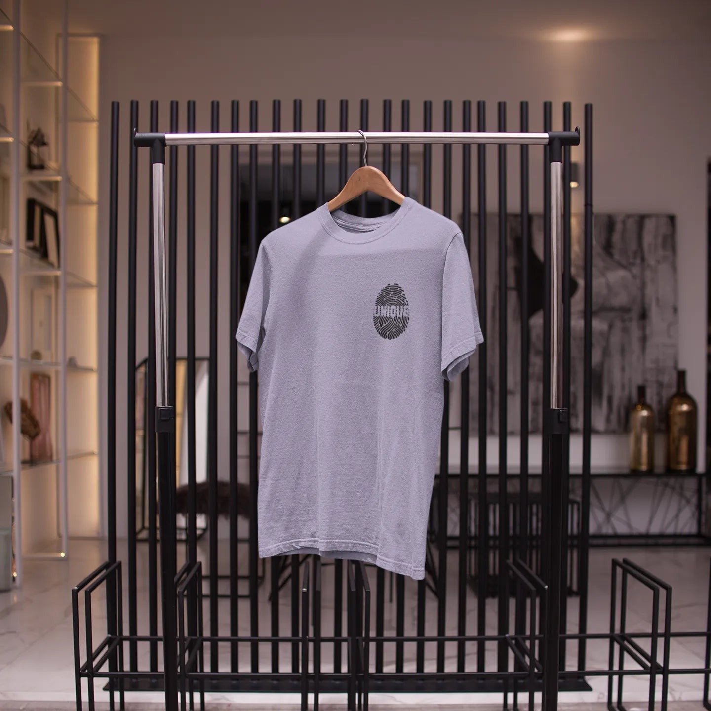 Gray t-shirt on a hanger against a black metal rack in a store setting