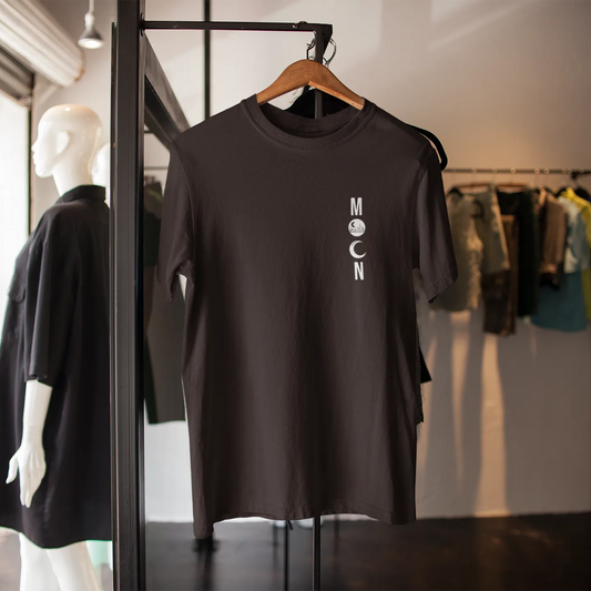 Black t-shirt with 'MOON' logo on a hanger in a clothing store.